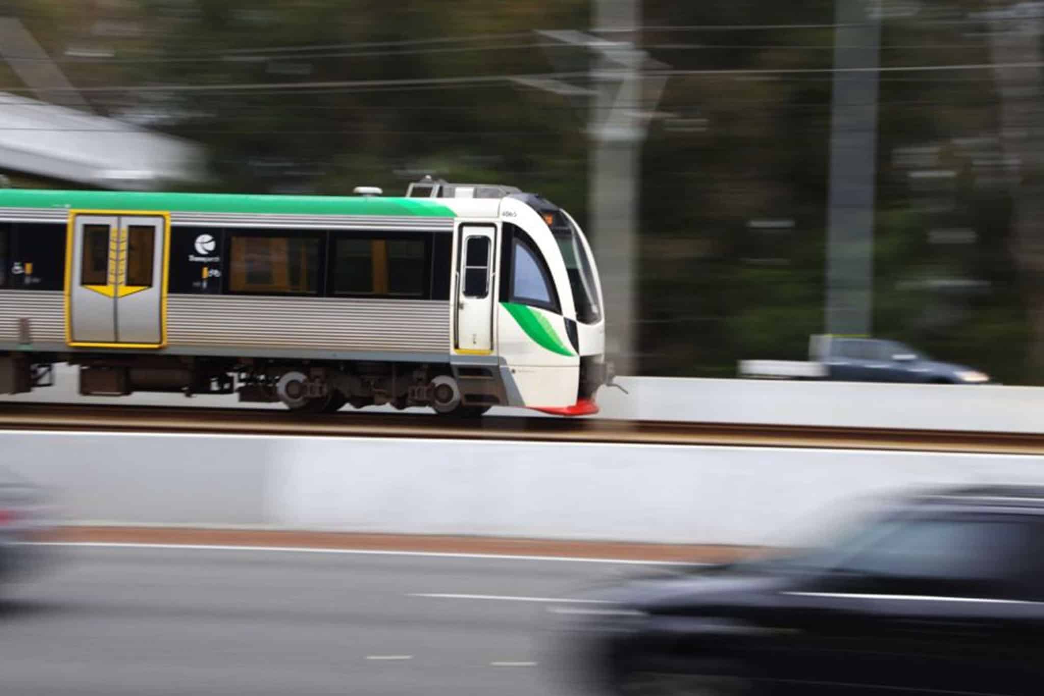 A train with cars behind it travels down the tracks, with fire safety equipment visible nearby.