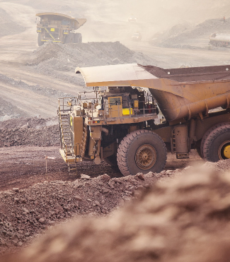 A large dump truck drives through a mine, equipped with fire safety equipment.