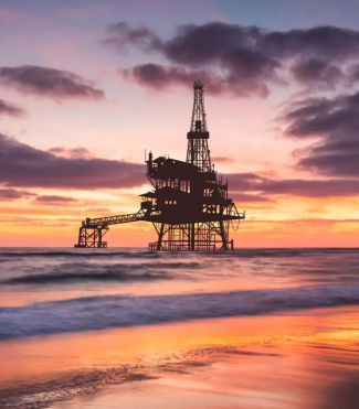 An oil rig at sunset in the ocean, with fire safety equipment visible. A serene scene with safety measures in place.