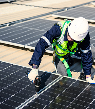 A man in a safety vest and hard hat working on solar panels, equipped with fire safety gear.