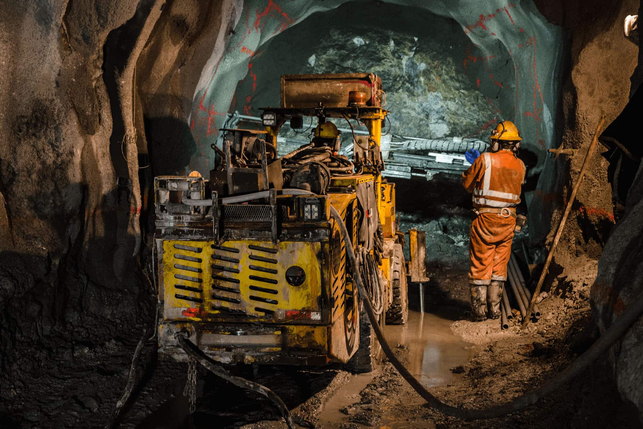 A construction worker in a tunnel, equipped with fire safety gear, diligently carries out their work.