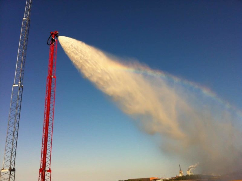 A fire truck sprays water, forming a rainbow. Demonstrating fire safety equipment in action.