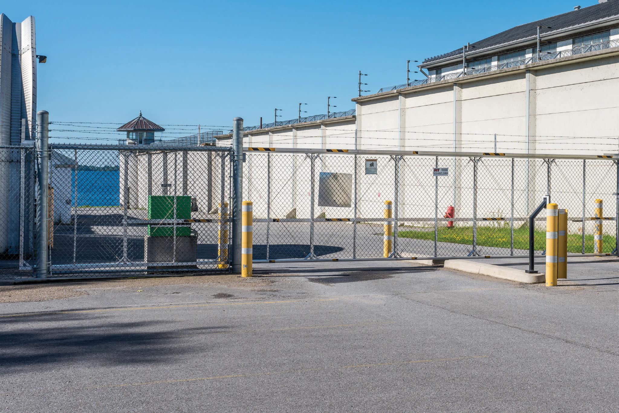 A large white building with a fence and gate, equipped with fire safety equipment.