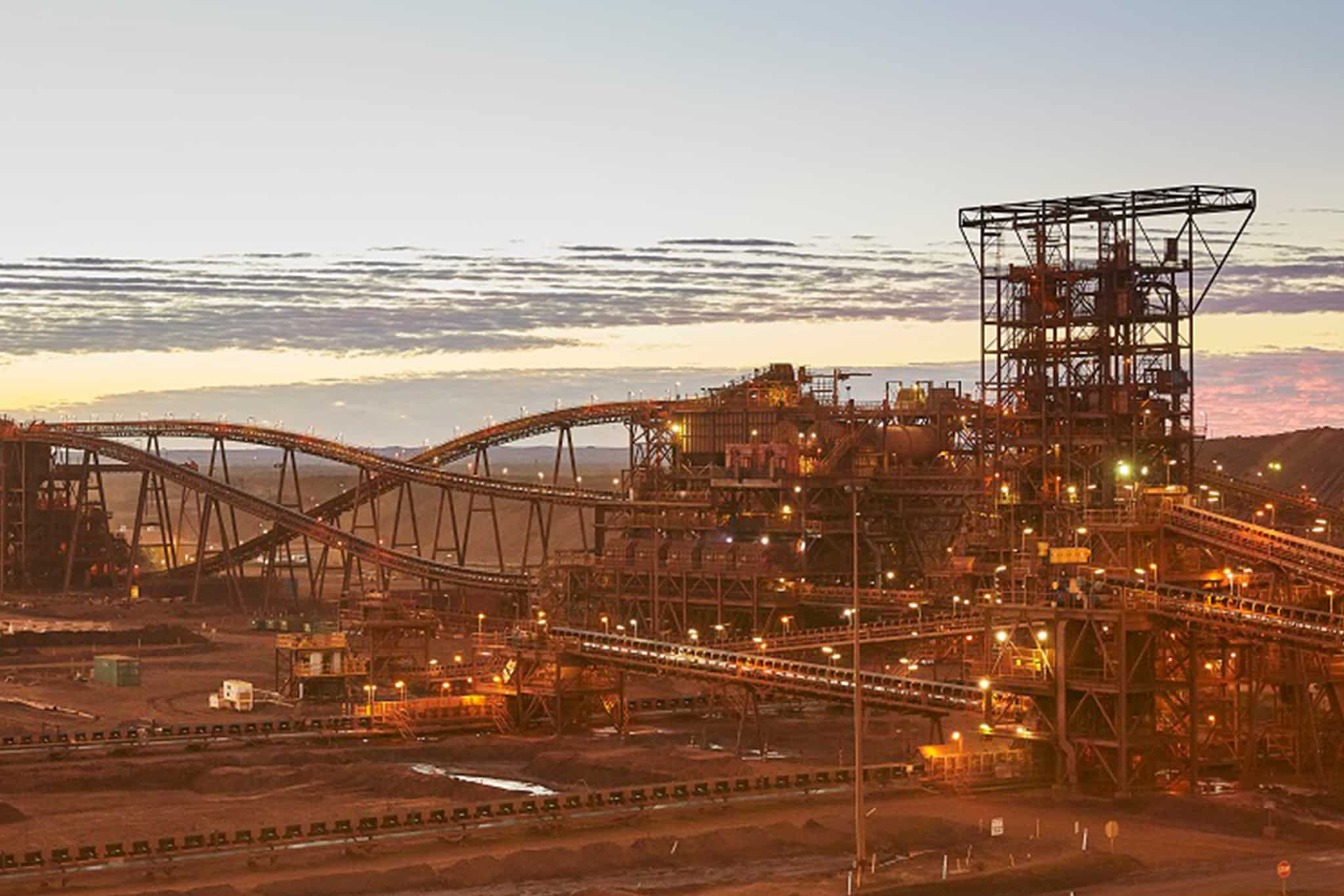 An iron ore mine at sunset with a large crane, surrounded by fire safety equipment.